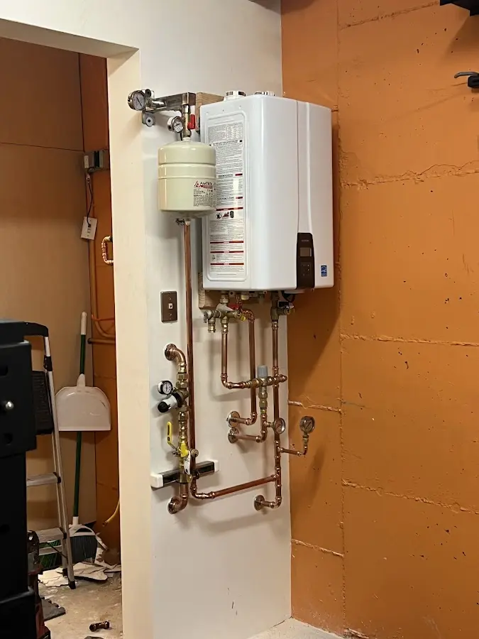 Plumbing technician inspecting water heater connections in Princeton